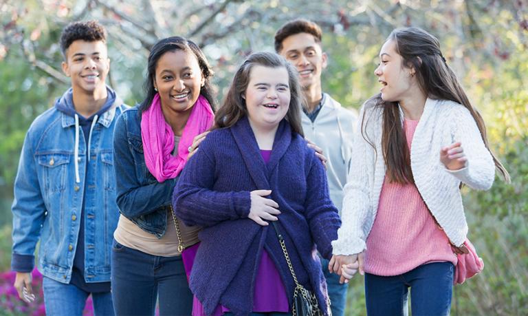 Des adolescents diversifiés marchent en groupe dans un parc.