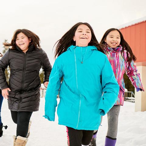 Un groupe de jeunes heureux courent dehors dans la neige