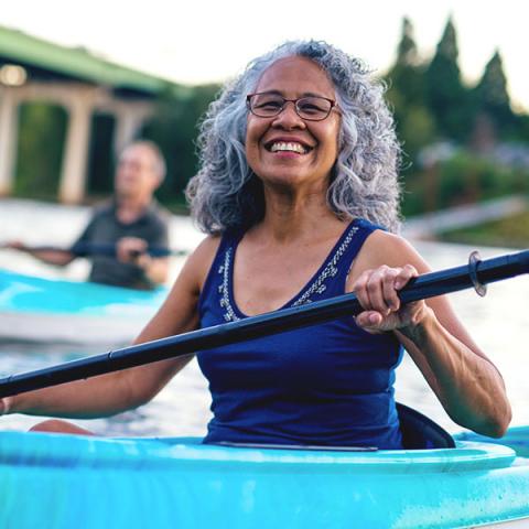 A person smiles while kayaking.