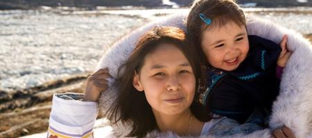 Mother and daughter outdoors in winter clothes.