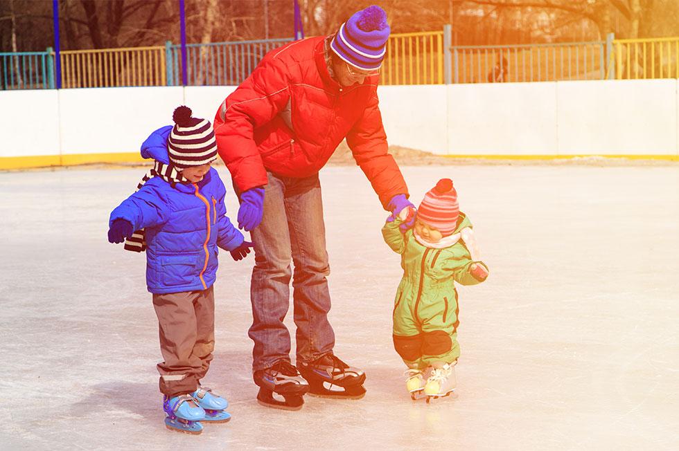 Un parent patinant avec deux enfants.