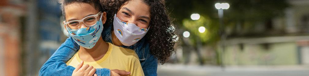 Des jeunes avec des masques respiratoires s’enlacent dehors.