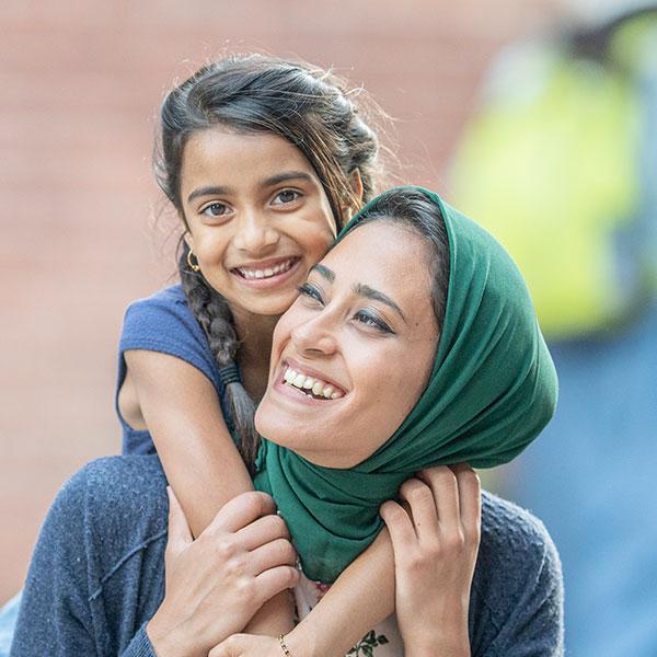 Mother and daughter hugging and laughing outdoors