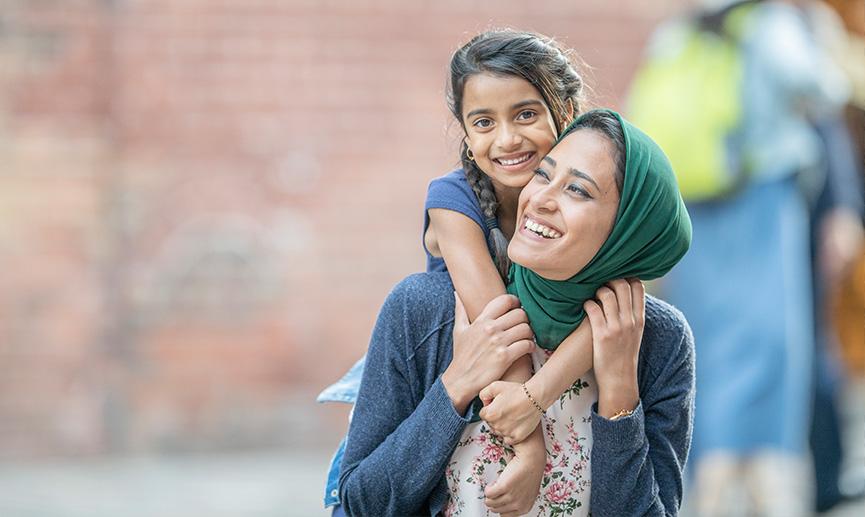 Mother and daughter hugging and laughing outdoors