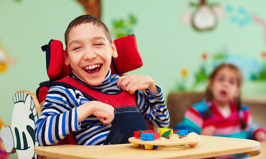 A young boy in a wheelchair laughs while playing with games 