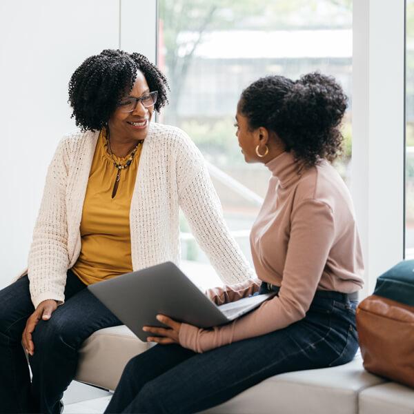 A mentor is talking to a young mentee in a lobby.