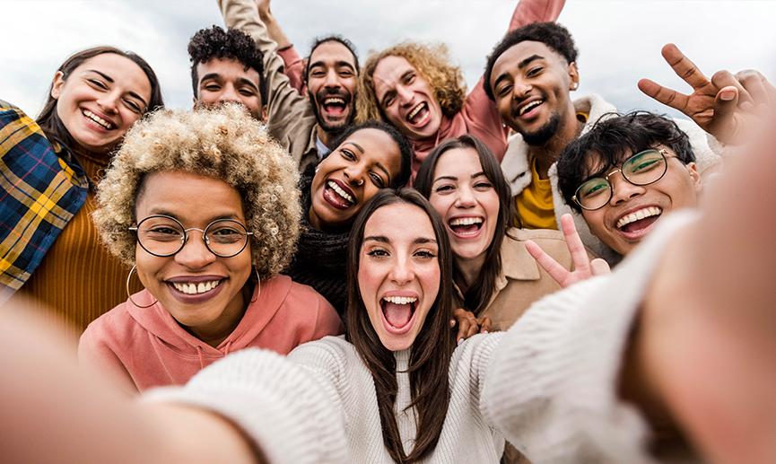 Un groupe d’amis multiracial se prend en photo en souriant à la caméra.