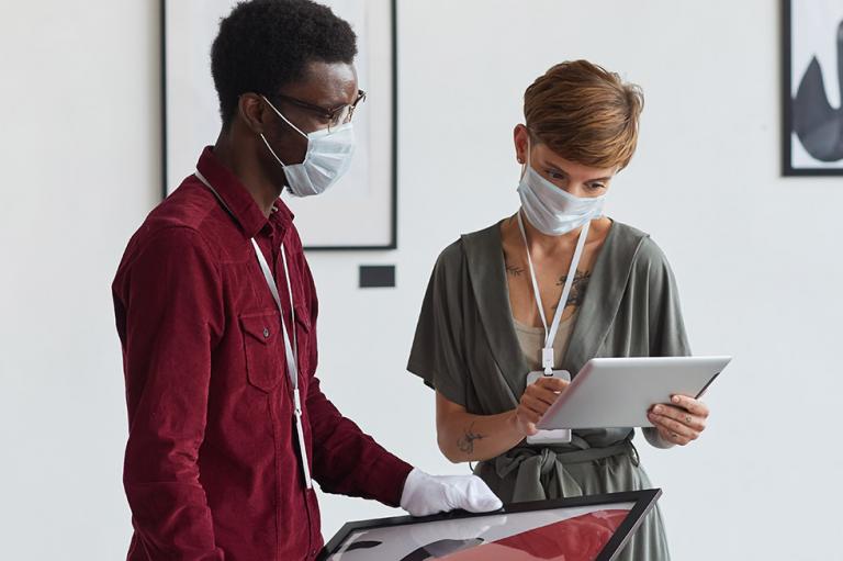 Two people in an art gallery wearing masks.