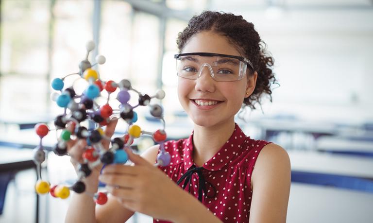 Une jeune fille travaille sur une expérience scientifique en classe.
