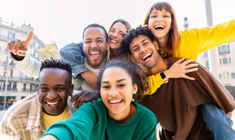 Young group of happy multiracial friends taking selfie portrait in the city.