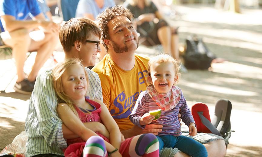 Une jeune famille de quatre, assise pour écouter des groupes à un festival de musique en plein air.