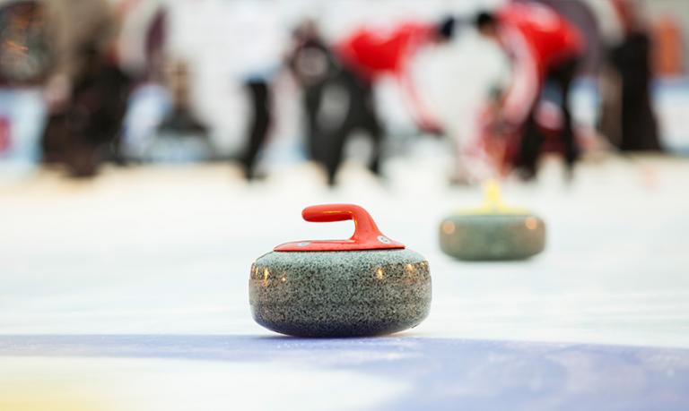 A close up of a curling rock on a curling rink.